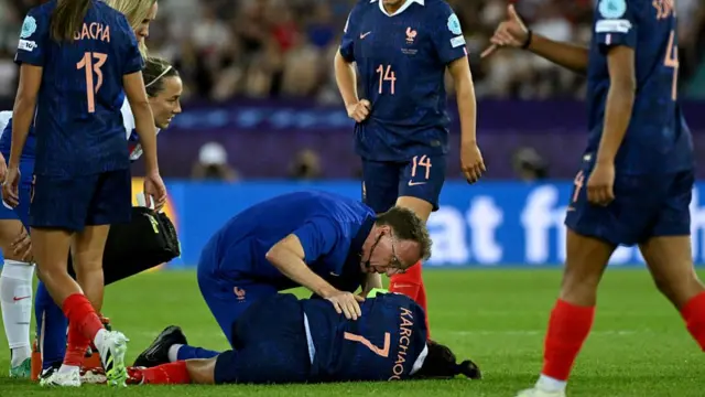 A medic checks France's midfielder #07 Sakina Karchaoui as she lies on the pitch during the UEFA Women's Euro 2025 Group D football match between France and England
