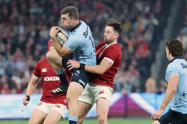 Waratahs' Lawson Creighton (2nd L) is tackled by British and Irish Lions' Hugo Keenan