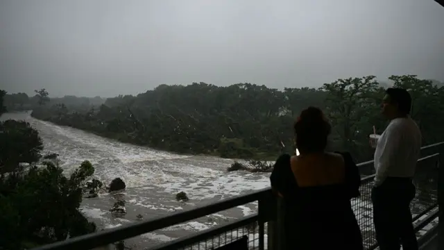 Two people look on at the flooding cause by flash floods and heavy rainfall.