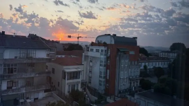 An orange sunrise rises from the Porto skyline