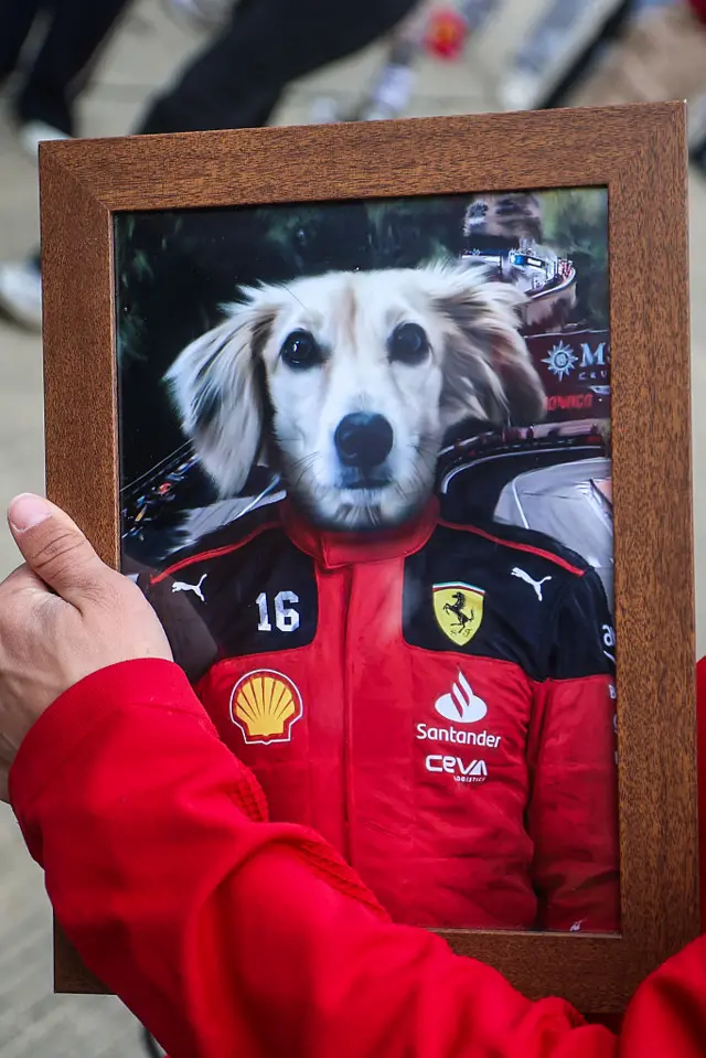 fan holds an image of Leo Leclerc in a ferrari suit