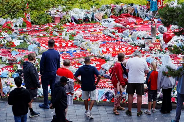 Dozens of scarves and flowers lined up outside Anfield Stadium