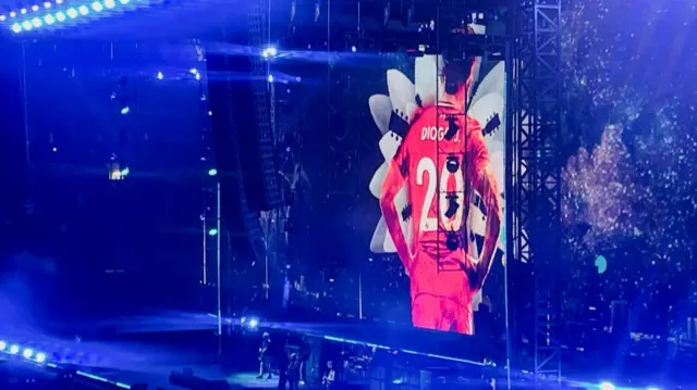 A picture of Liverpool and Portugal footballer Diogo Jota is projected on a screen behind the British rock band Oasis