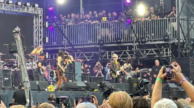 Musicians on stage with the backs of people's heads in the audience