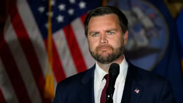 US Vice President JD Vance wearing a dark suit and red tie
