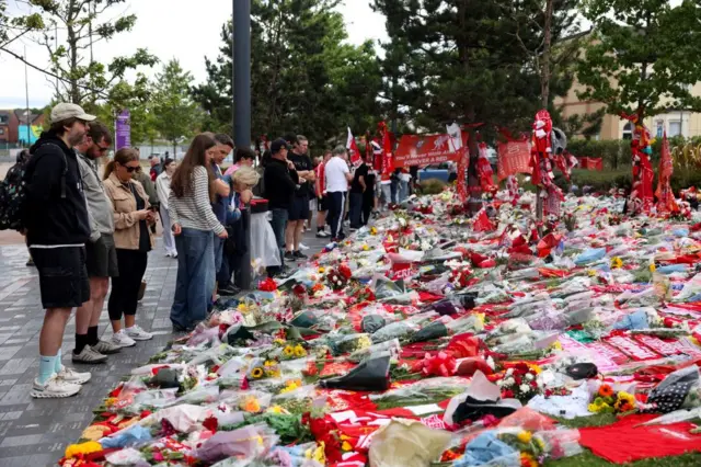 Fans pay their respects outside Anfield Stadium where hundreds of flowers and scarves line the floor