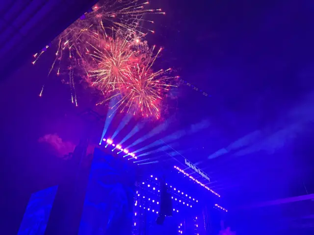 Fireworks go off above the stadium which is bathed in blue light