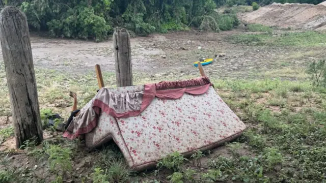 white and pink flowered couch flipped upside down, its ruffles turned over on a patch of grass