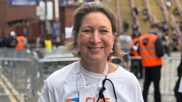 A woman in a white t-shift is smiling at the camera