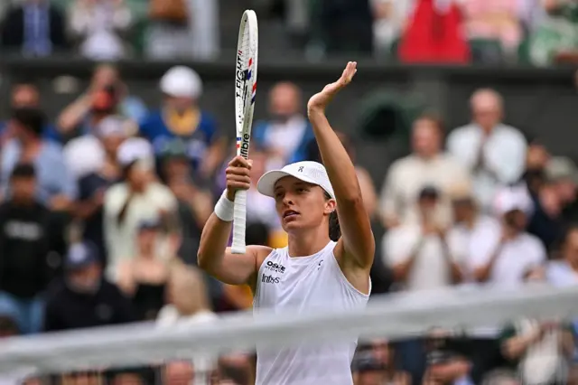 Iga Swiatek holds up her racquet