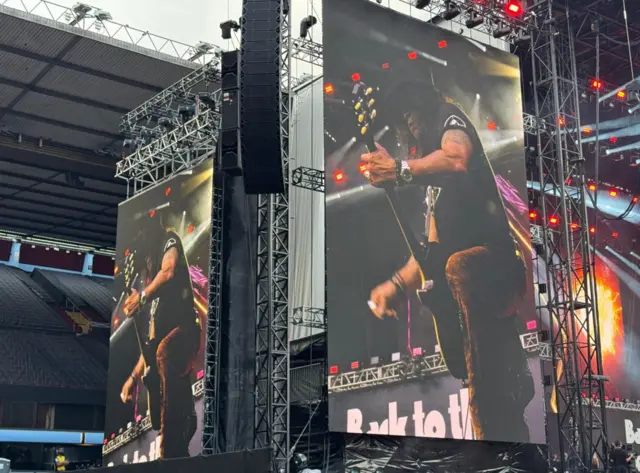 A performer seen on two big screens
