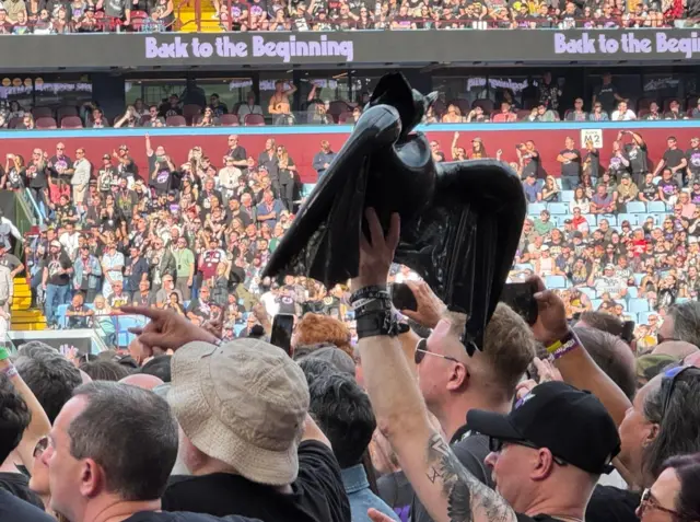 Someone in the crowd on the ground holding a bat in the air, alongside other people