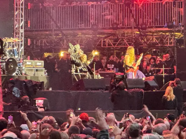 A man sat on a black throne and fans with their hands in the air