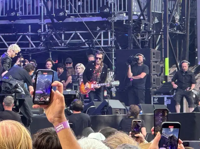People on stage with the backs of heads of people in the audience.