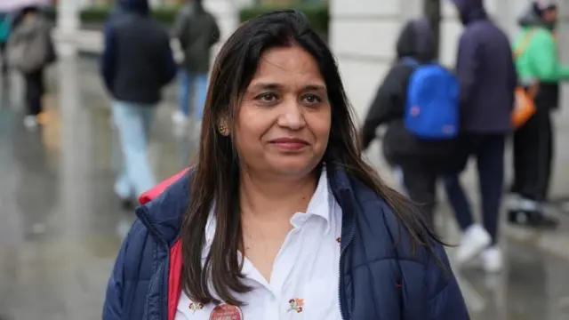 Seema Misra wearing a blue coat