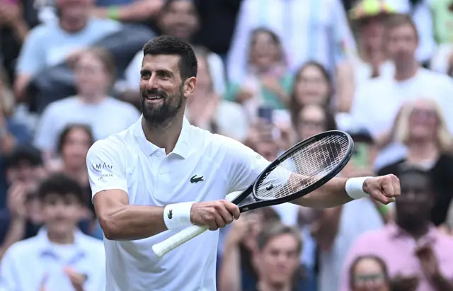 Novak Djokovic holds up his tennis racquet