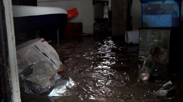 Inside of home filled with mud and flood water, debris and personal objects floating on the surface