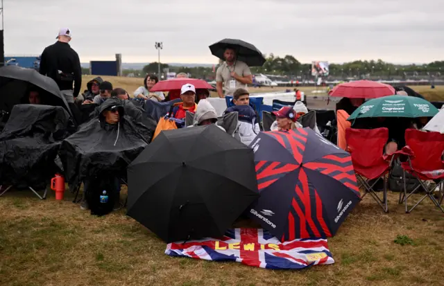 Fams shelter under umbrellas at Silverstone