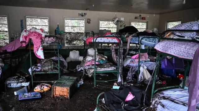 Mattresses and rubbish scattered inside a cabin at Camp Mystic full of bunk beds.