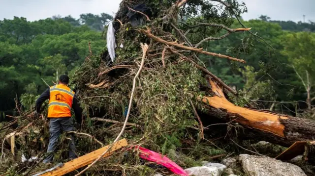 A man stands next to a fallen tree following flash floods.