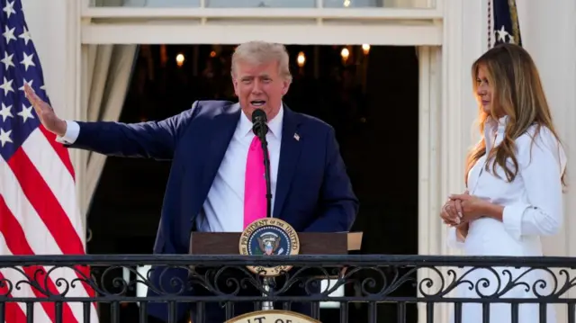 Donald Trump on balcony, speaking into microphone. Melania stood to his right.