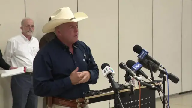 Kerr County Sheriff Larry L. Leitha speaking at a news confrence, wearing a cowboy hat