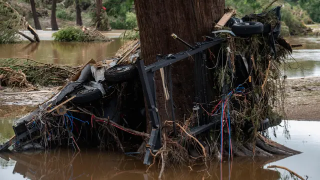 Car wrapped round a tree after flooding in Ingram, Texas
