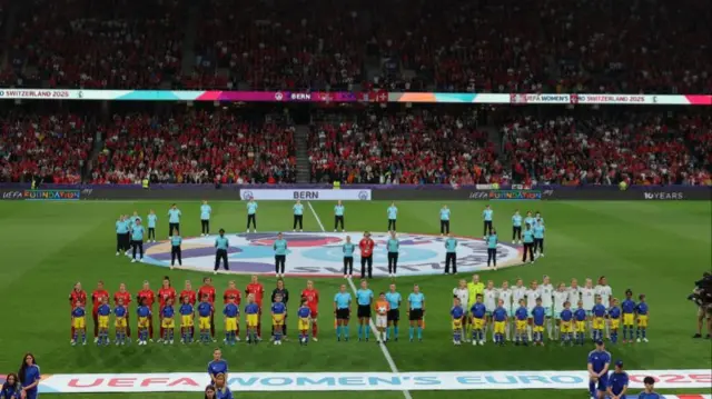 The teams line up with young mascots during the national anthems before the match