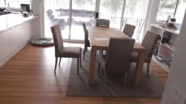 An image of a dinning room. Six chairs surround a wooden oak table