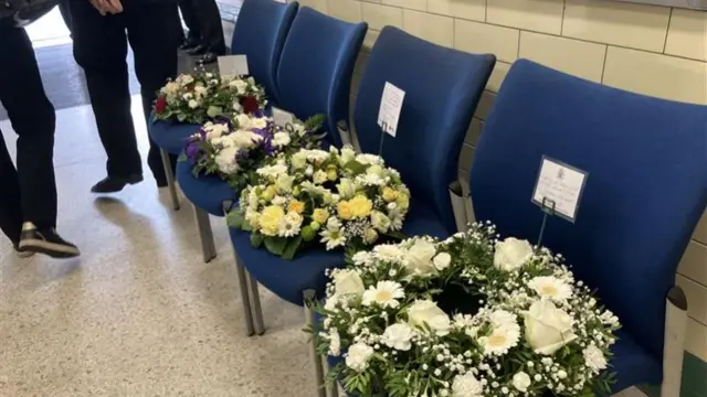Four floral wreaths left on blue chairs at Russell Square
