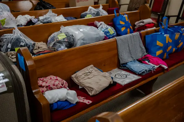 Clothes, folded and sorted, on wooden church pews