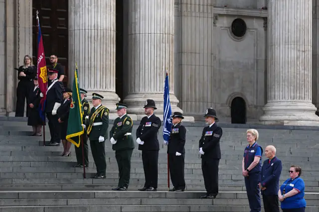 Representatives of the Salvation Army, London Ambulance Service, Metropolitan Police and London Underground line the steps