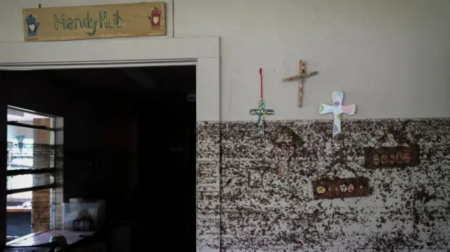 Crosses hang from a wall with flood marks