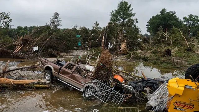 Destroyed van in front of tress destroyed following the floods