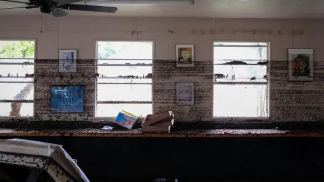 Frames hang from a wall with streaks of flood marks