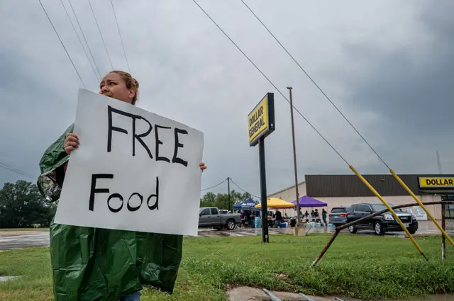 A volunteer displays a sign for free food for people in need of relief