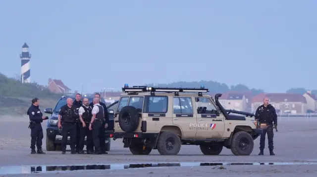 French police officers watch a group of people thought to be migrants board a small boat leaving the beach at Gravelines, France, in an attempt to reach the UK by crossing the English Channel.