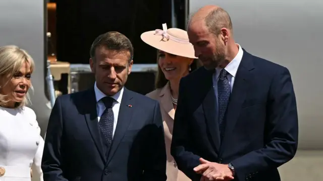 Macron and Prince William walk together in front of Macron's plane - they are both wearing suits