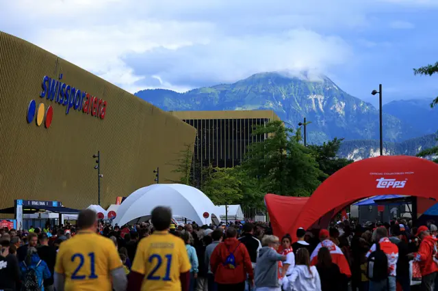 Fans of Poland and Sweden arrive at the stadium as the Mountain towers in the background