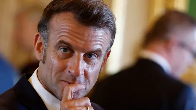 Macron looks ahead, eyebrows raised.