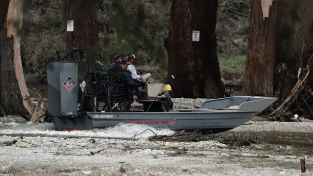 Three members of an emergency response team in an airboat searching an area along the Guadalupe river in Texas.