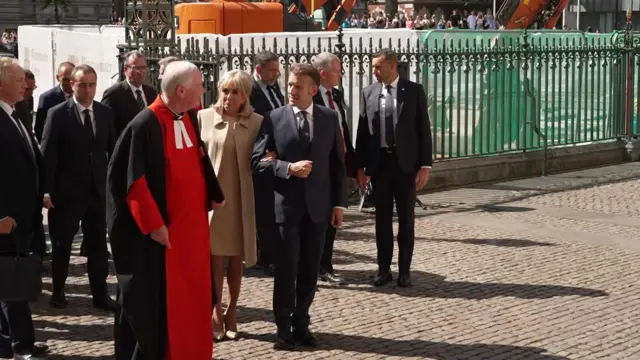 Macron and Brigitte walking arm in arm alongside a bishop