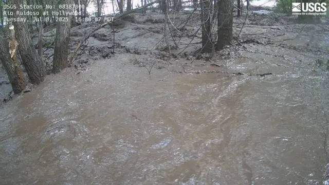 River Ruidoso, completely flooded, with water rushing over trees and the riverbank