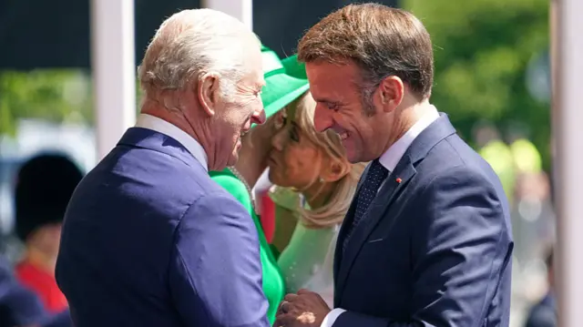 Macron and Charles smile at each other.