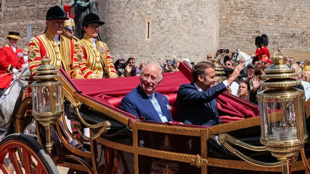 King Charles and Macron waving to crowds in a carriage