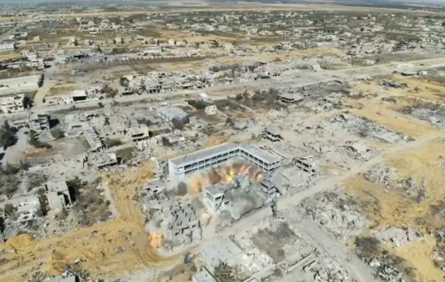 Screen grab of drone footage showing a building marked as girls' school on satellite mapping being demolished