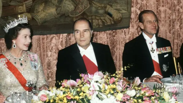 Elizabeth II, Mitterrand and Philip at a decorated dining table