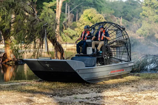Two men in a search and recovery team launch a fan boat on Guadalupe River