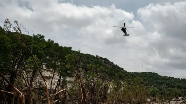 A helicopter flies above the Guadalupe river