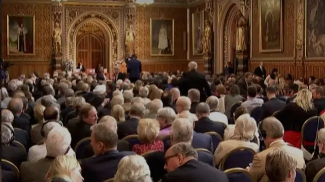 Back of lots of peoples heads sitting in fancy room